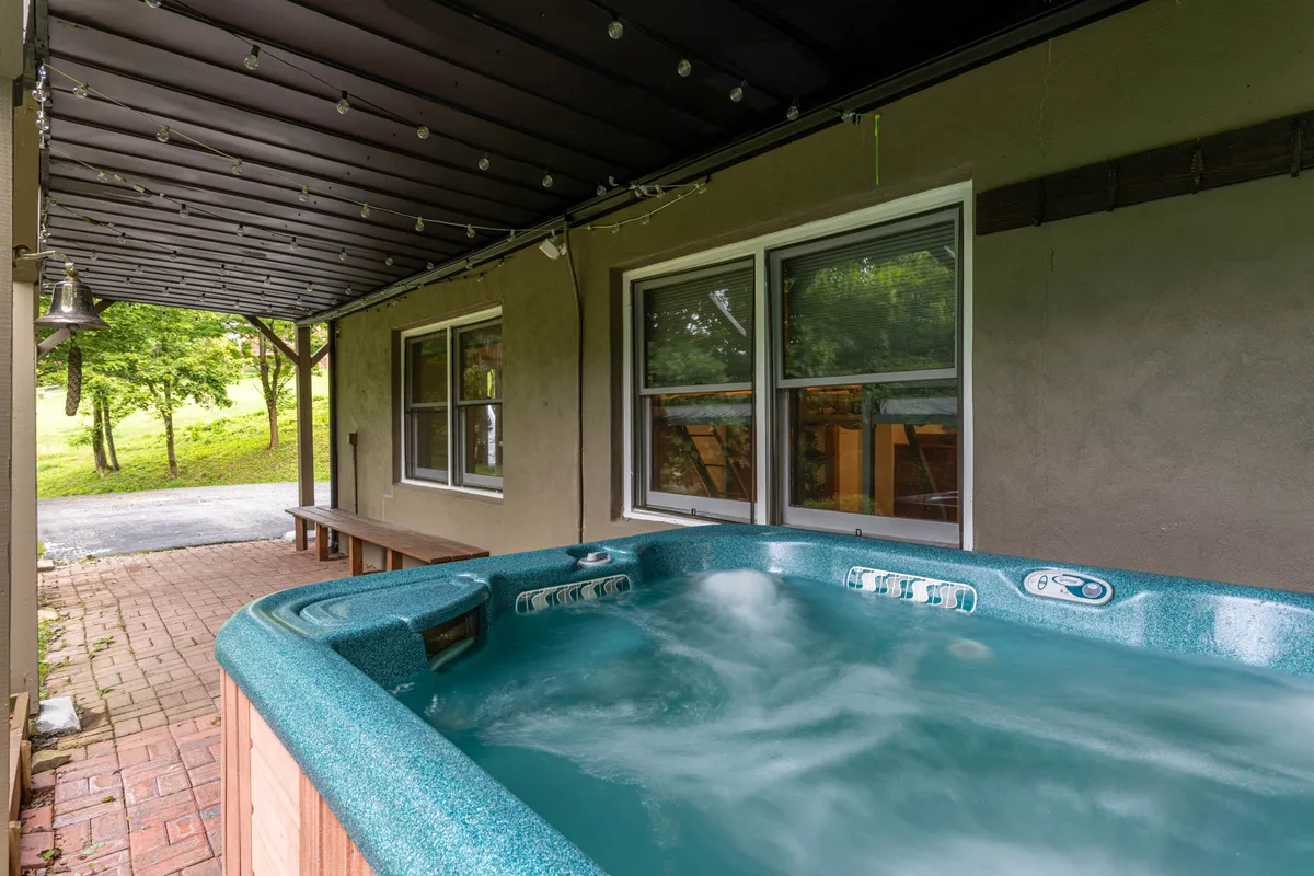 A bubbling hot tub sits on a patio surrounded by lush gardens and an outdoor seating area. The space invites relaxation while offering beautiful garden views, and is ideal for social gatherings or unwinding after a day of outdoor activities.