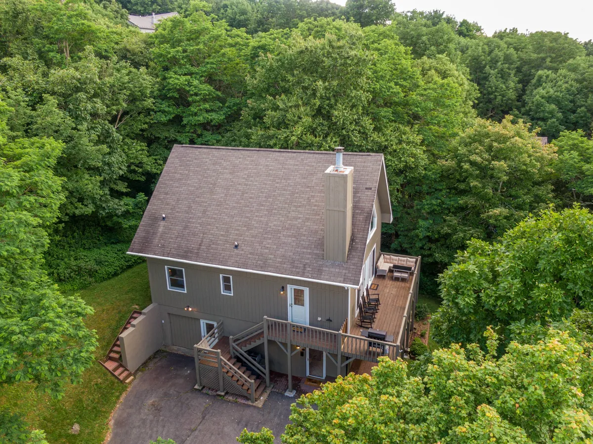 A wooden deck surrounded by dense greenery and featuring a prominent chimney, providing a peaceful and secluded spot for outdoor gatherings and relaxation. The setting encourages guests to enjoy sunsets, nature, and the mountain air.